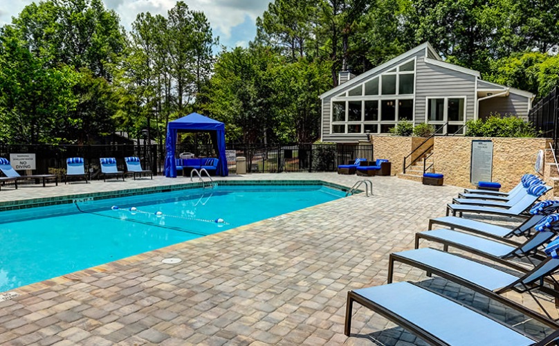 Swimming pool with blue chaise lounges on sundeck at 700 Riverchase Apartments in Hoover, AL